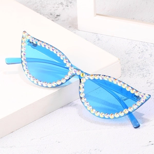 Blue cat eye sunglasses with rainbow rhinestones on a minimalist white stone pedestal