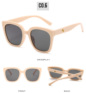Detail view of beige oversized sunglasses with gold metal accents and dark grey lenses