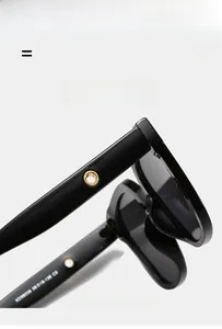 Detail of black sunglasses arm featuring golden circular metal trim and elastic frame