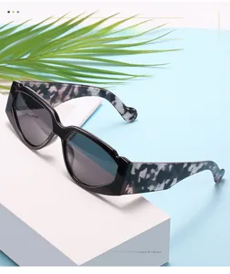 Dettaglio di occhiali da sole alla moda con montatura piccola, lenti nere e motivo marmorizzato