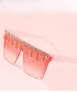 Close-up of pink oversized square sunglasses with sparkling rhinestone fringe detail