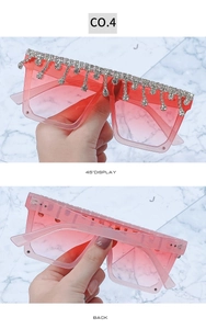 Macro detail of oversized square sunglasses with red gradient lenses and silver fringe rhinestones