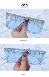 Detail of blue oversized square sunglasses with sparkling rhinestone tassels and frame