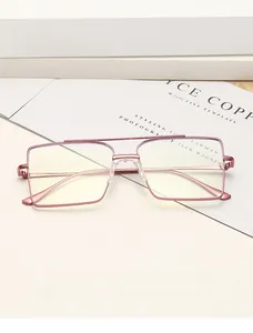 Détail d'une monture de lunettes carrée en métal or rose à double pont sur fond blanc