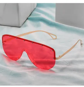 Détail de lunettes de soleil masque avec verres rouges, monture dorée et rivets décoratifs