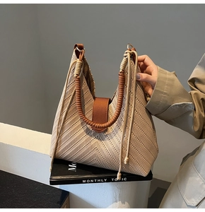 Close-up of beige knitted tote bag featuring V-shaped texture and brown leather strap details
