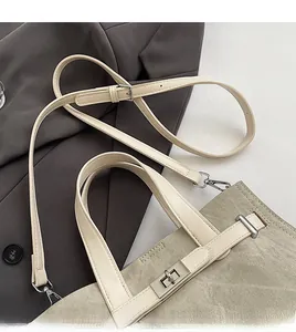 Detail of detachable shoulder strap and silver metal buckle on khaki canvas tote bag