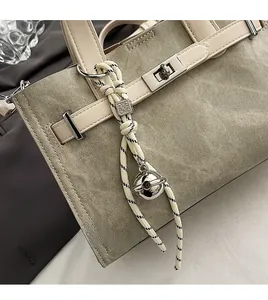 Detail of canvas tote bag featuring metal turn-lock and woven rope charm with metal dice