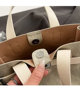 Detailed close-up of leather tote bag with magnetic metal clasp and refined stitching