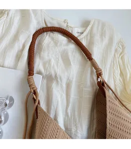 Close-up of brown and beige braided rope strap with metal ring on woven tote bag