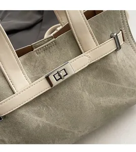 Detail of silver twist lock and cream leather trim on taupe denim tote bag