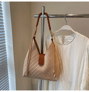 Detail of beige woven hobo bag featuring brown leather strap and V-shaped texture