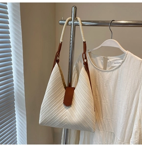 Detail of herringbone woven tote bag with brown leather clasp and bicolor shoulder strap
