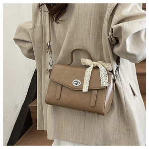 Dettaglio borsa vintage marrone con chiusura a rotazione argento e fiocco di pizzo crema