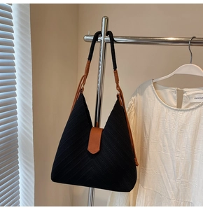 Close-up of black V-pattern knit tote bag with woven strap and leather buckle detail