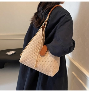 Close-up of beige woven tote bag with brown twisted rope strap and chevron pattern