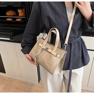 Detail of beige tote bag with textured finish, metal buckle and braided rope handles