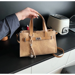 Detail of camel suede leather tote bag featuring silver twist lock and bell charm