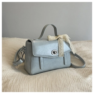 Gros plan du sac cabas bleu-gris clair avec nœud en dentelle et fermoir tournant