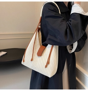 Detail of herringbone woven tote bag with brown leather strap and contrast buckle
