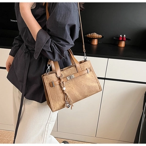 Detail of vintage brown textured tote bag with metallic lock and stylish tassel charm