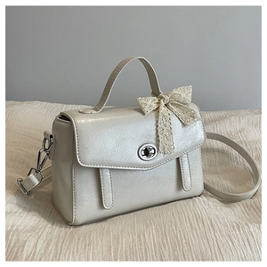 Détail du sac vintage crème avec nœud en dentelle et fermoir rotatif argenté