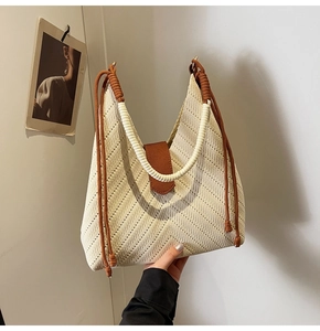 Detail of woven tote bag with brown leather strap and side fringe accents
