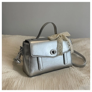 Détail du sac à bandoulière argenté métallisé avec nœud en dentelle et fermoir tournant