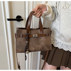 Close-up of vintage brown leather tote with metal buckle and woven strap detail