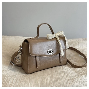 Détail d'un sac cabas marron avec fermoir rotatif argenté et accessoire en dentelle blanche