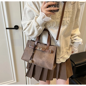 Detail of vintage brown tote bag with metal twist lock and woven bell charm accessory
