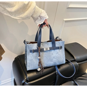 Detailed close-up of retro denim blue tote with contrast handles and metal turn-lock buckle