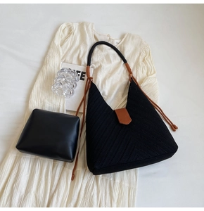 Detail of black woven tote and leather pouch on a pleated skirt with stylish accessories