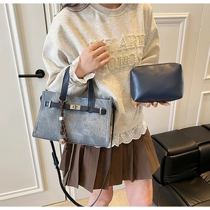 Detail of grey washed tote bag with metal twist lock and navy blue pouch accessory