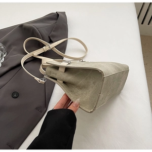 Detail of light green bucket bag showing textured leather finish and white shoulder strap