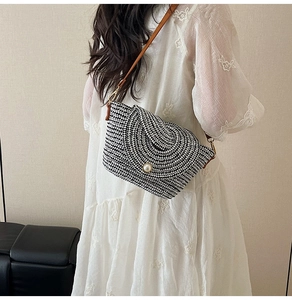 Détail du sac à bandoulière tressé noir et blanc avec un grand bouton perle élégant