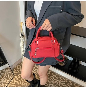 Detail of red crossbody bag featuring heart-shaped zipper pull and smooth leather texture