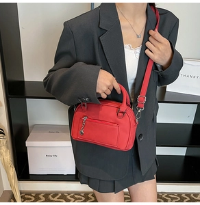 Close-up of red nylon pillow bag with heart pendant and adjustable shoulder strap