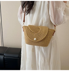 Détail d'un sac en paille tressé main avec fermoir perle et fil métallique doré brillant