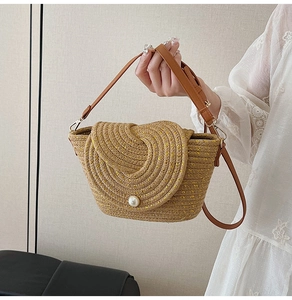 Gros plan du sac tissé main marron avec un grand bouton perle et des reflets dorés