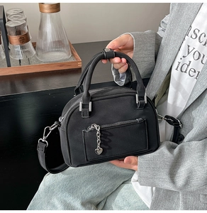 Detail of black Boston bag featuring heart-shaped zipper pull and smooth matte texture