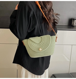 Détail du sac tressé vert clair avec boucle en perle et bandoulière en cuir