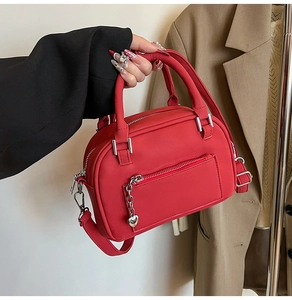 Detail of red Boston bag with heart charm, matte leather texture and silver hardware