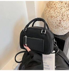 Detail of black matte bowling bag with silver heart chain charm and front zipper pocket