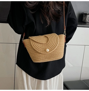 Détail du sac en paille tressée avec accent perlé et bandoulière en cuir marron