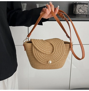 Détail d'un sac en paille tressée avec un fermoir perle et une bandoulière en cuir