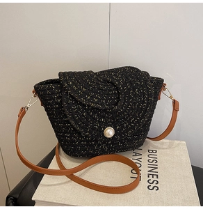 Détail du sac tressé noir avec texture en soie dorée, fermoir perle et lanière en cuir