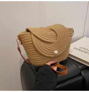 Détail d'un sac en paille tissée avec boucle en perle et bandoulière en cuir marron