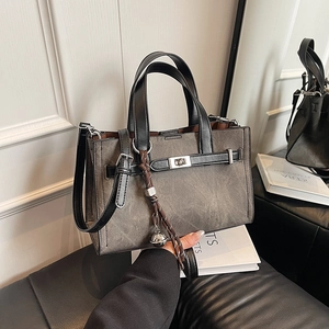 Minimalist grey commuter tote bag with black handles and metal twist lock detail
