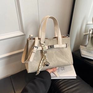 Minimalist beige tote bag with contrasting trim and adjustable shoulder strap for commuting